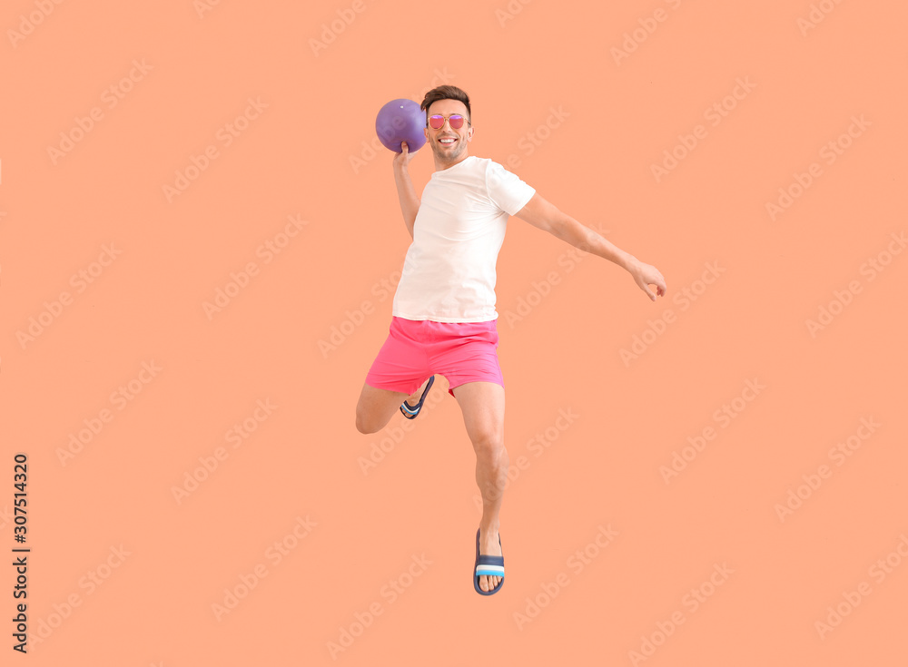 Jumping young man with ball on color background