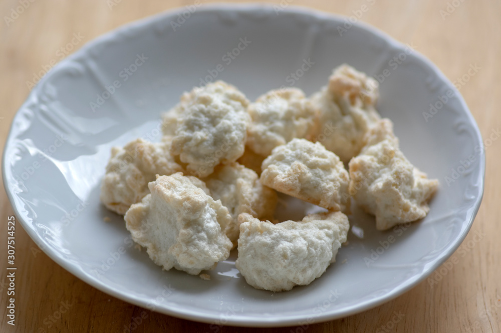 Coconuts made of egg whites, sugar and shredded coconut on white plate on wooden table, group of Christmas sweets Coconuts made of egg whites, sugar and shredded coconut on white plate on wooden table, group of Christmas sweets
