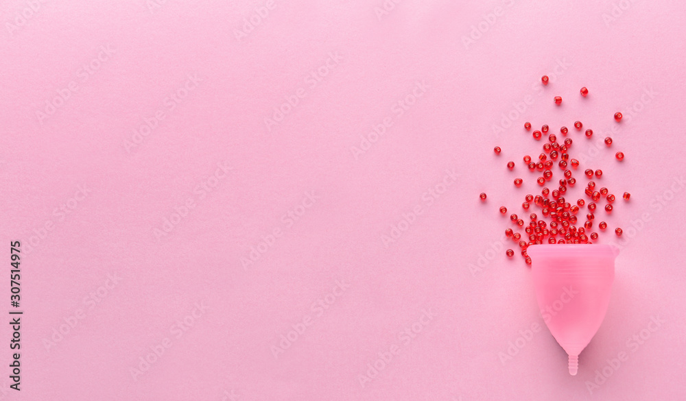 Menstrual cup with red beads on color background