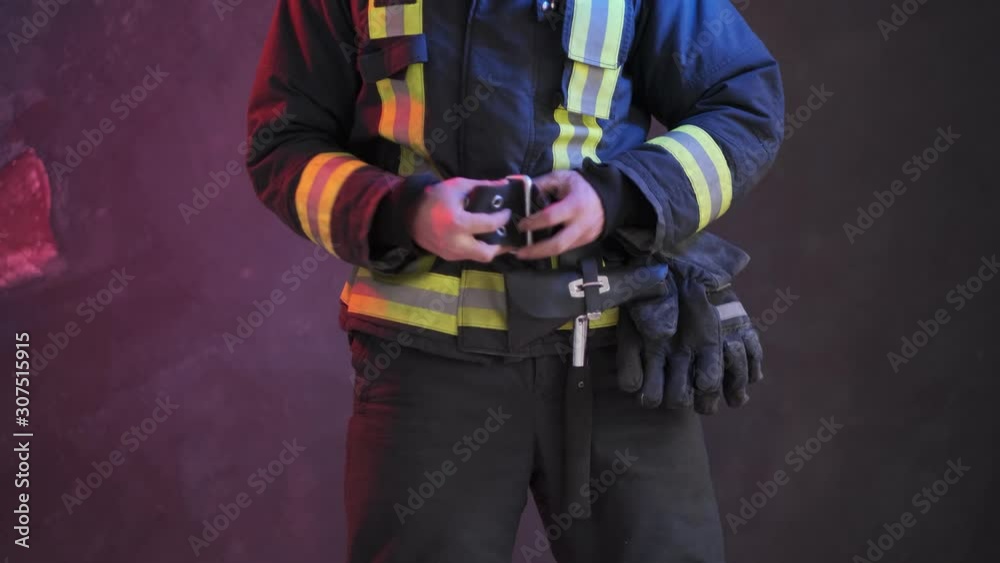 Firefighter wears uniform while standing against a gray wall
