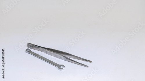 Steel tweezers and small wrench isolated on white background. Isolated view.