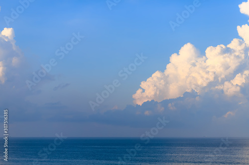 The beautiful background image of the vast ocean has a deep blue sea and a golden glow from the sun and a large cloud above the horizon.