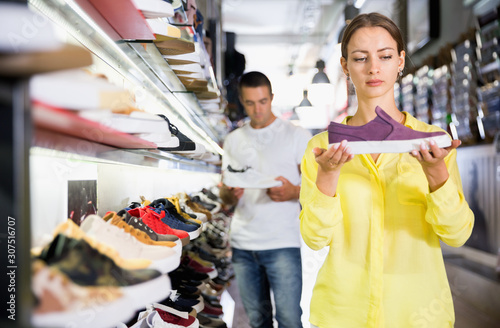 Young positive woman shopping casual sneakers in modern store