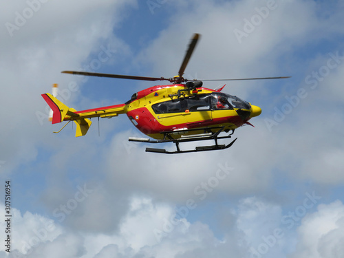 Civil protection helicopter in take-off maneuver over blue sky with white clouds in Martinique Island. French West Indies Antilles