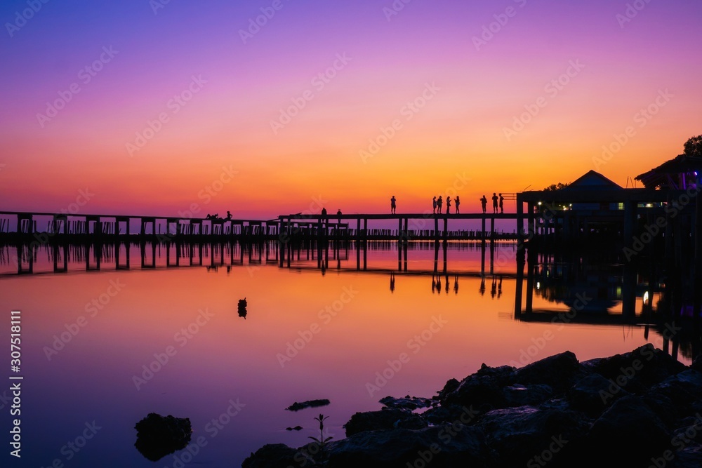 Naklejka premium wooden pier at the sea with beautiful bloody sunset. sunset seascape at a wooden jetty. Wood bridge