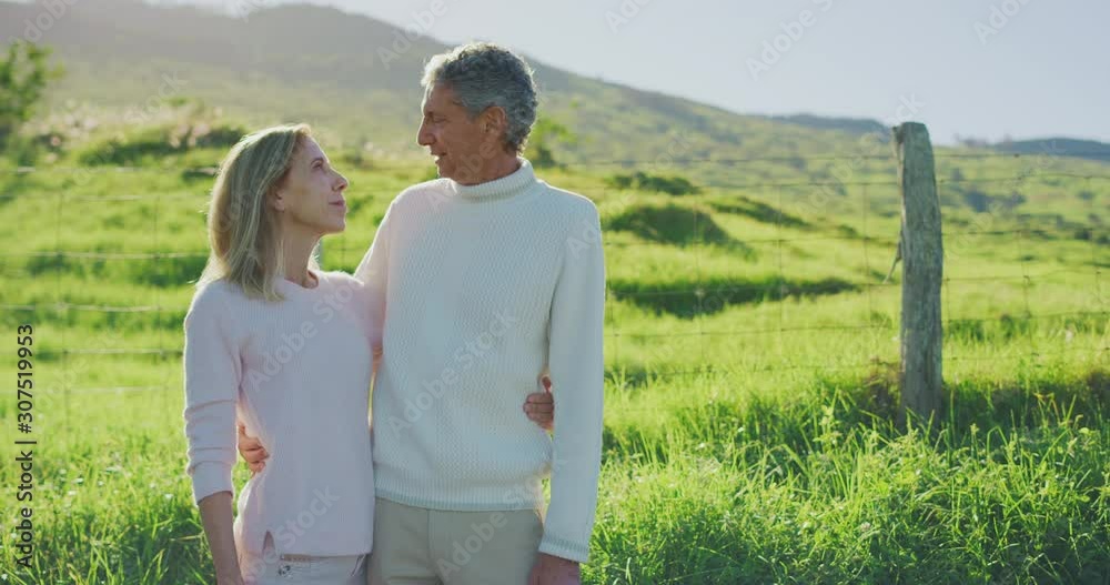 Older retired couple enjoying a romantic kiss outdoors together with golden sunny green fields in the background, senior couple enjoying their retirement years together, a long and happy marriage Older retired couple enjoying a romantic kiss outdoors together with golden sunny green fields in the background, senior couple enjoying their retirement years together, a long and happy marriage