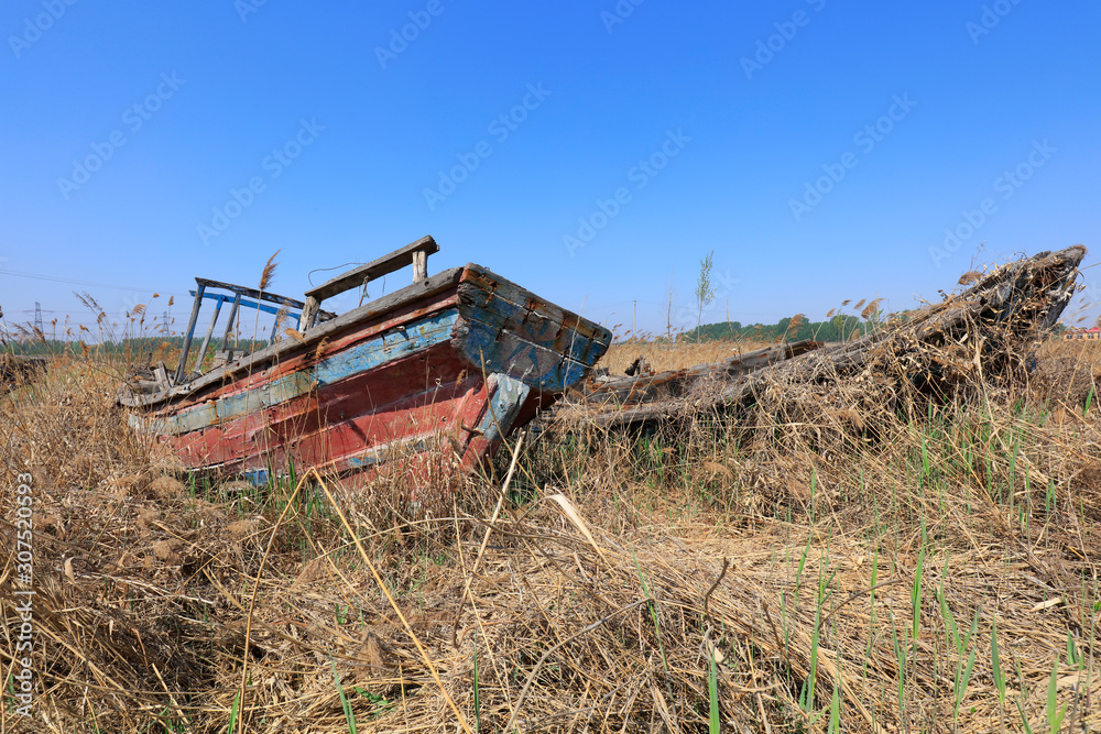 Fototapeta premium The broken wooden boat is on land