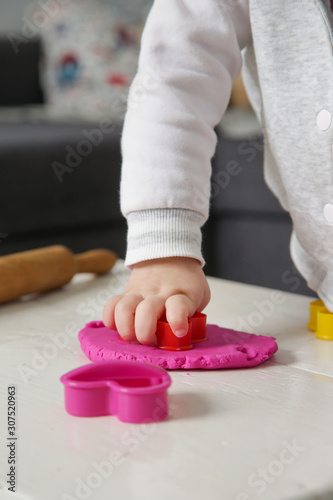 Toddler girl playing with modelling clay. Play dough allows kids to develop fine motor skills  strengthen fingers  hands and wrists and to be naturally curious and explore the world using their senses