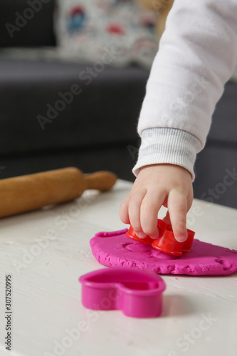 Toddler girl playing with modelling clay. Play dough allows kids to develop fine motor skills, strengthen fingers, hands and wrists and to be naturally curious and explore the world using their senses