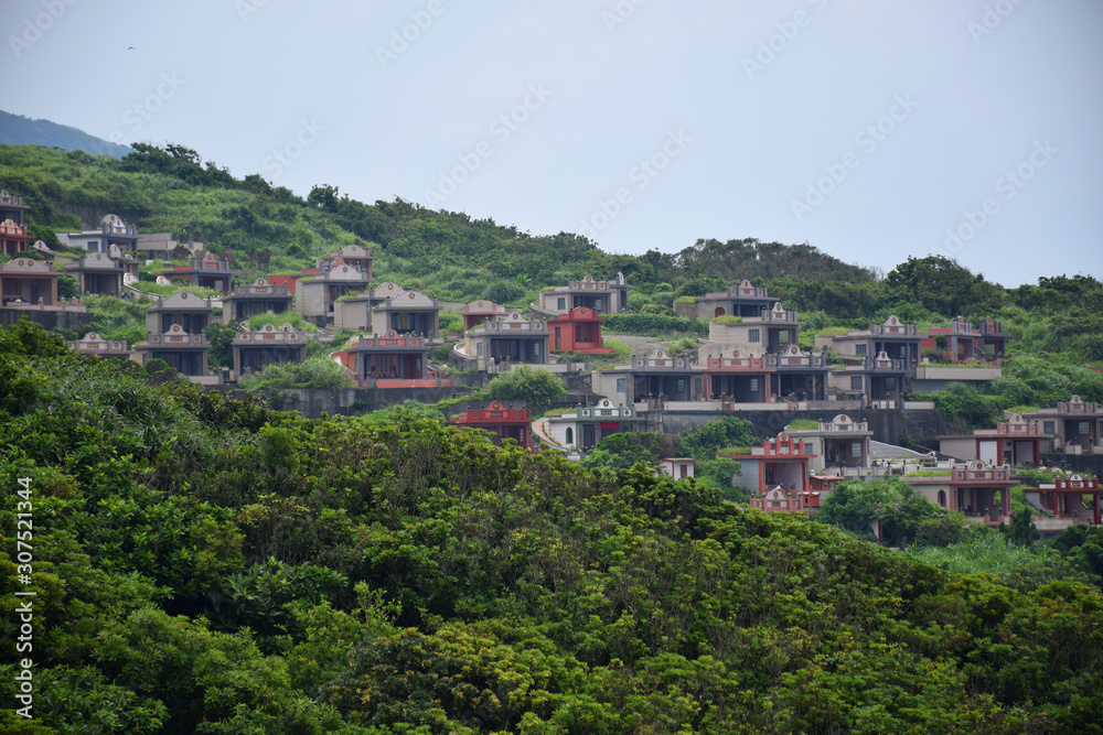 Taiwanese cemetery on a cliffside within a forest, with colorful shrines, Taipei, Taiwan