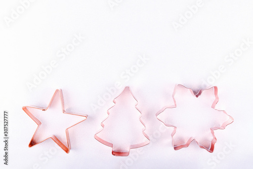 Flatlay with star  snowflake and holiday tree copper cookie cutters on white sparkling background. Holiday  Christmas and New Year concept. Cozy homey details. Flat lay top view background. Horizontal
