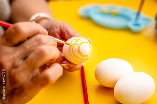 Woman decorating a easter eggs with dots and lines.