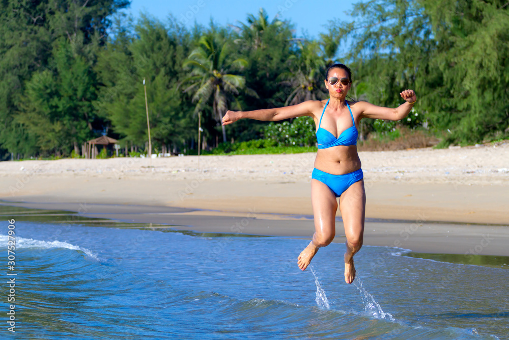 Fototapeta premium Woman sexy and bikini blue jump on wave at beach