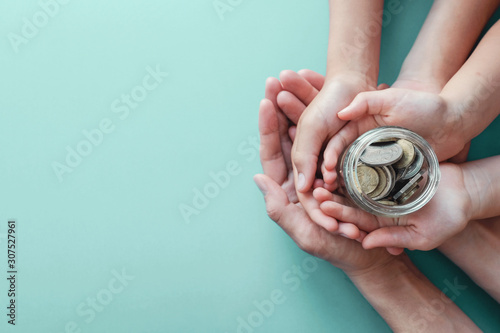 Фотография child and adult holding money jar, donation, saving, charity, family finance pl