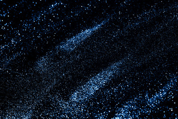 Splash of blue sparkles on black background. Color of the year 2020 concept.