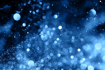 Splash of blue sparkles on black background. Color of the year 2020 concept.