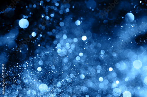 Splash of blue sparkles on black background. Color of the year 2020 concept.