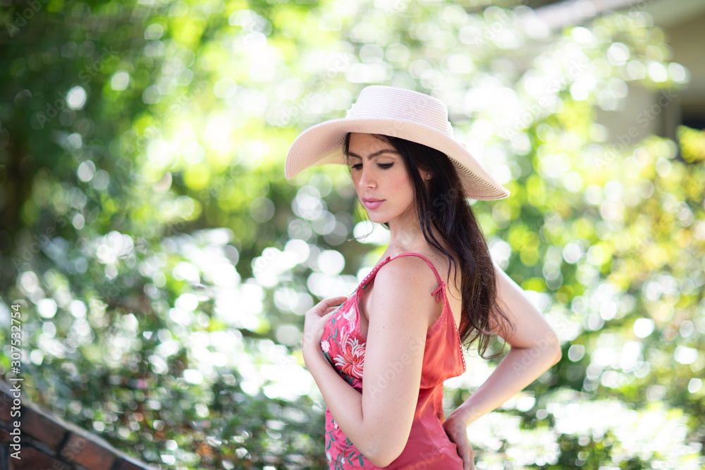 Portrait of a beautiful young Italian woman wearing a straw hat in sunny warm weather day.