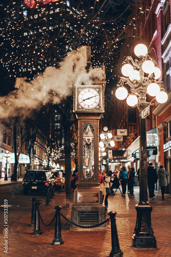 The famous Steam Clock in Gastown in Vancouver city with cars light trails at night photo