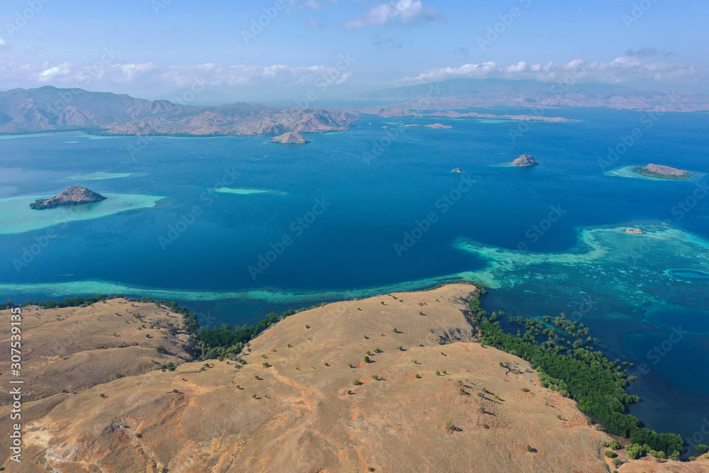 Fototapeta premium Aerial and top view the beautiful blue ocean and fisherman village at the remote island called Papagarang located in Komodo National Park, Indonesia.