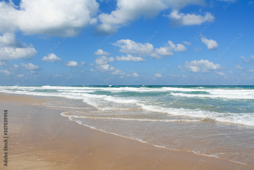 Sea foam on the sandy beach at Bat Yam, Israel. Waves on the blue stormy sea. Mediterranean coastline. Travelling picture. Turquoise water and sandy beach