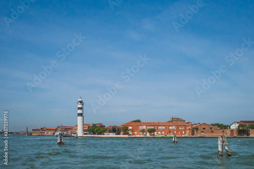 Lighthouse and buildings by water, in Murano, Venice, Italy