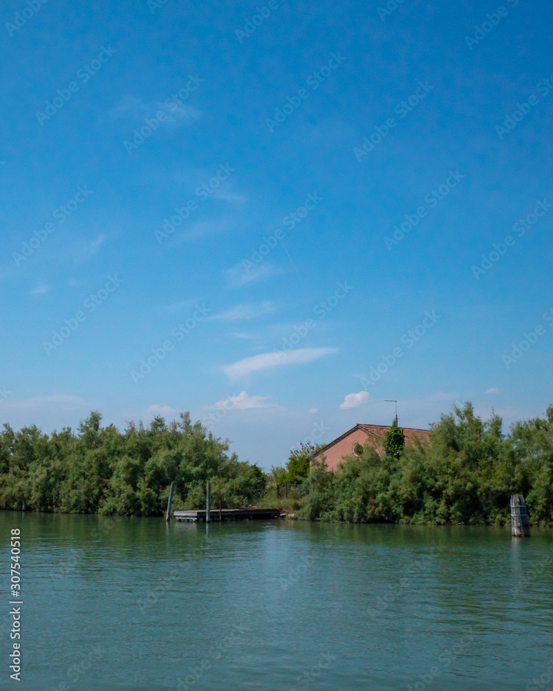 House behind trees by water near island of Torcello, Venice, Italy House behind trees by water near island of Torcello, Venice, Italy