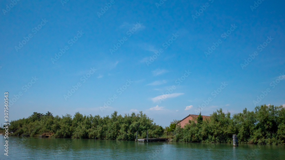 House behind trees by water near island of Torcello, Venice, Italy