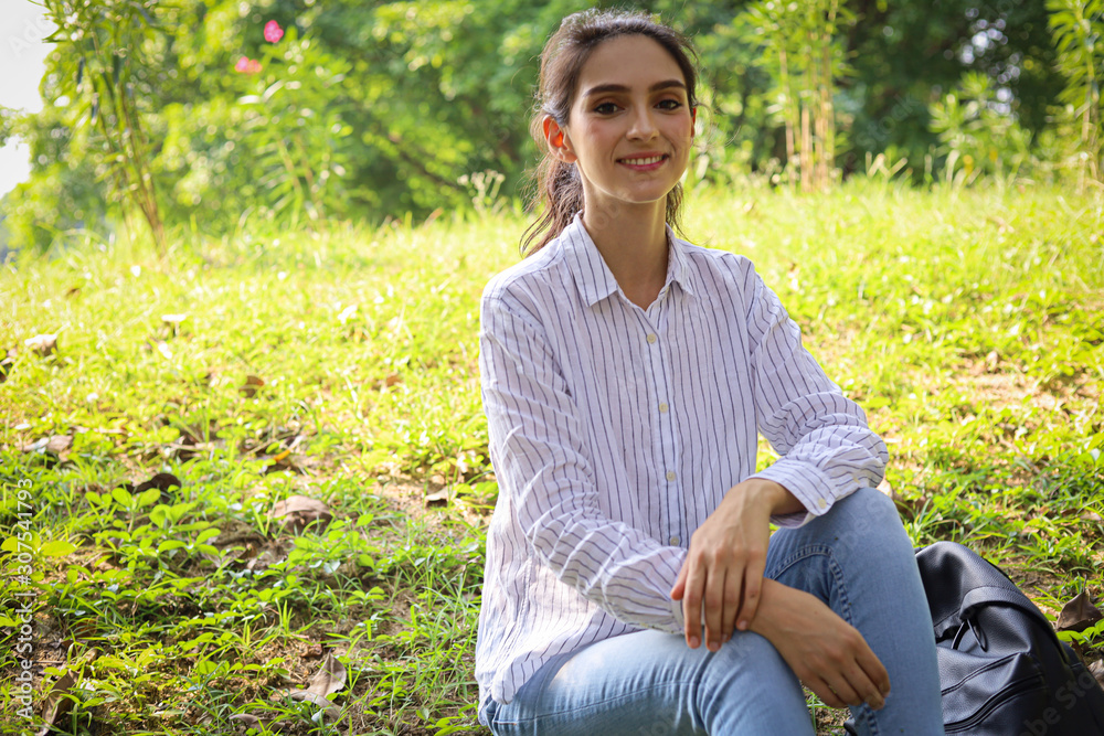 Obraz premium Beautiful woman sitting relaxation in holiday weekend on green grass in the garden.