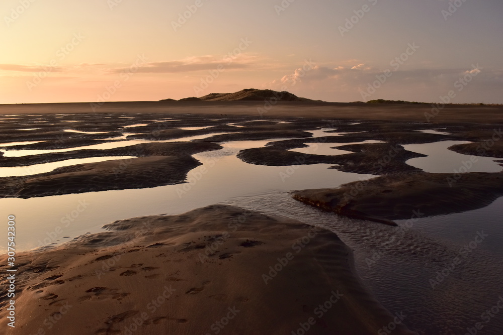 Obraz premium A small puddles in the sand after low tide in sunset light
