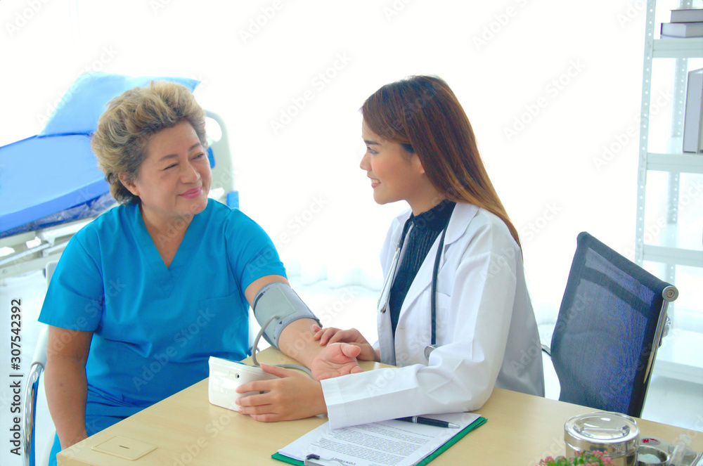 A female doctor checking blood pressure of a patient in the hospital A female doctor checking blood pressure of a patient in the hospital