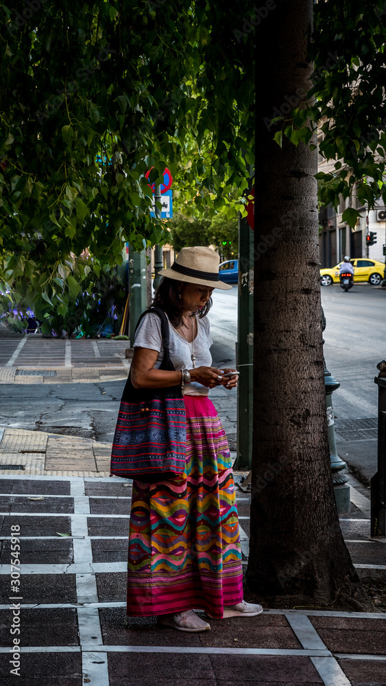 Asian woman in white t-shirt in Athens in sarong standing on street Asian woman in white t-shirt in Athens in sarong standing on street