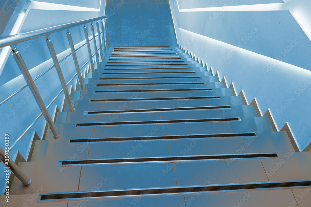 Modern classic stairs for descent down and rise up, illuminated by blue light. Dramatic background for creative. Soft selective focus. Modern classic stairs for descent down and rise up, illuminated by blue light. Dramatic background for creative. Soft selective focus.
