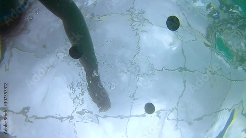 Underwater view of kids hand dropping coins into water. photo