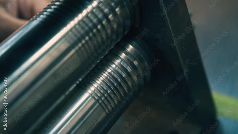 CU: professional jeweler forge-rolls piece of gold bar with machine forging rollers on table in light workshop closeup CU: professional jeweler forge-rolls piece of gold bar with machine forging rollers on table in light workshop closeup