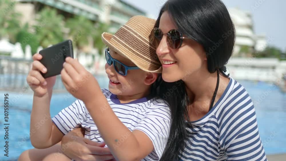Close-up happy travel family laughing taking selfie using smartphone near swimming pool Close-up happy travel family laughing taking selfie using smartphone near swimming pool