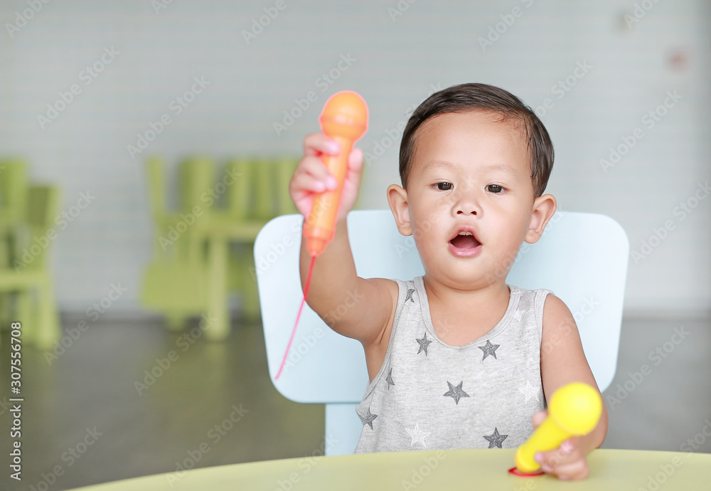 Portrait of little Asian baby boy sing a song by plastic microphone at children room. Portrait of little Asian baby boy sing a song by plastic microphone at children room.