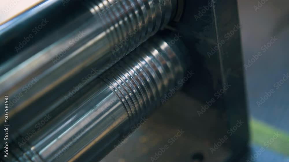 CU: professional goldsmith forge-rolls gold metal rod with mechanical forge-roller on table at workplace close view