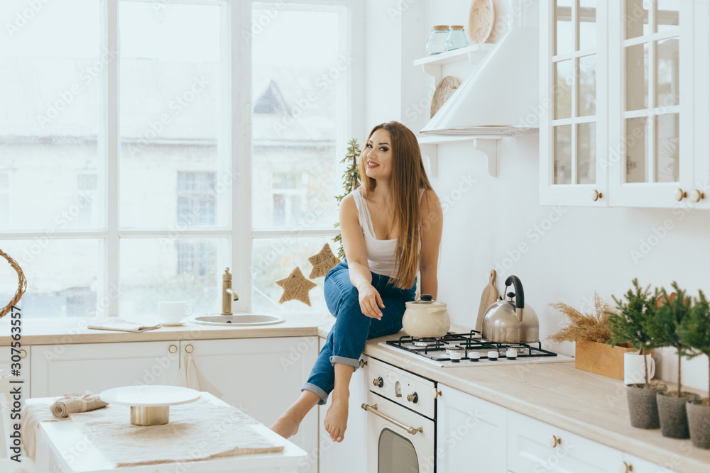 Portrait of a smiling young housewife in modern bright minimalistic Scandinavian kitchen Portrait of a smiling young housewife in modern bright minimalistic Scandinavian kitchen
