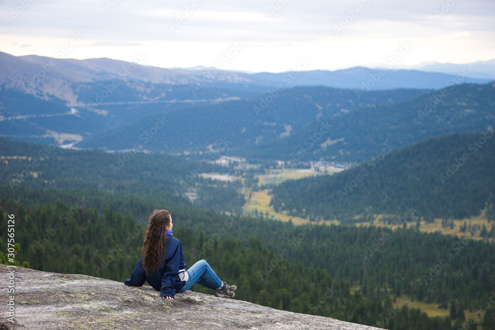 A girl sits on a rock and looks into the distance