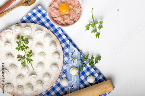 Pelmeni, little dumplings lie on a cutting board, sprinkled with gray flour, top view.