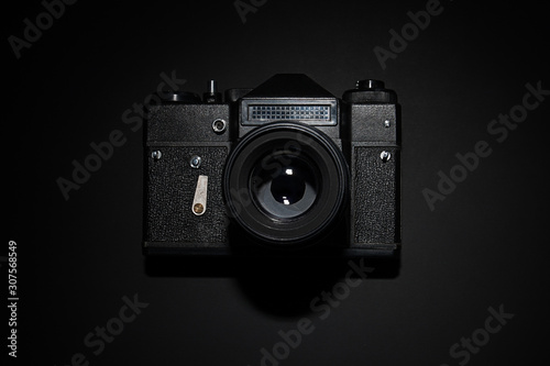Old black film camera on black background under spot light.