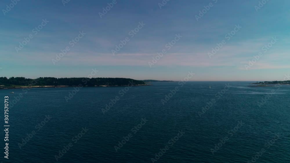 Slow aerial pull back over an inlet near Casco Bay toward a distant sailboat on Chebeague Island Maine Slow aerial pull back over an inlet near Casco Bay toward a distant sailboat on Chebeague Island Maine