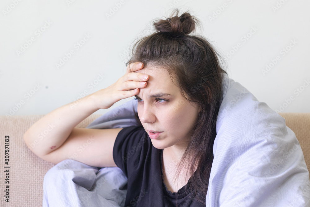 Sick young woman sitting at home with severe headache Sick young woman sitting at home with severe headache