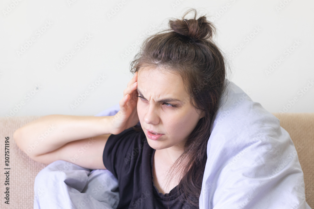 Sick young woman sitting at home with severe headache Sick young woman sitting at home with severe headache