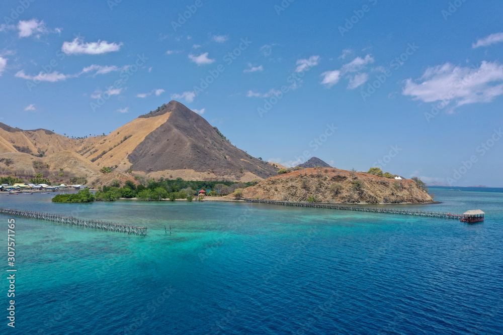 Beautiful view the Manjaja Island with blue and grean ocean, traditional wooden jetty and fisherman village located in Labuan Bajo, Indonesia. The popular destination for tourism.