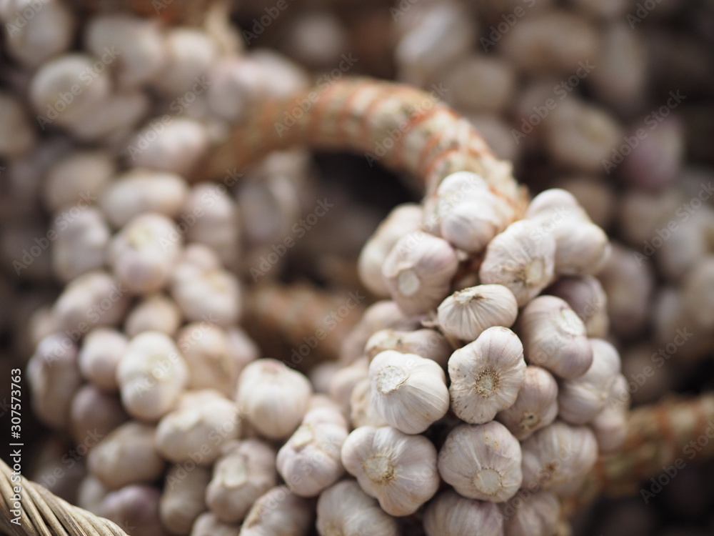 Garlic tied together in a bunch, placed in a woven basket Garlic tied together in a bunch, placed in a woven basket