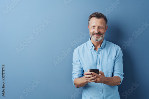 Happy relaxed man holding his mobile phone