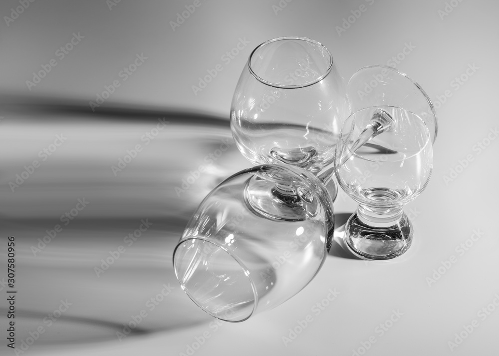 Wine and cognac glasses close-up. Collection of various glasses cast by shadow. Empty glass goblets. Wine and cognac glasses close-up. Collection of various glasses cast by shadow. Empty glass goblets.