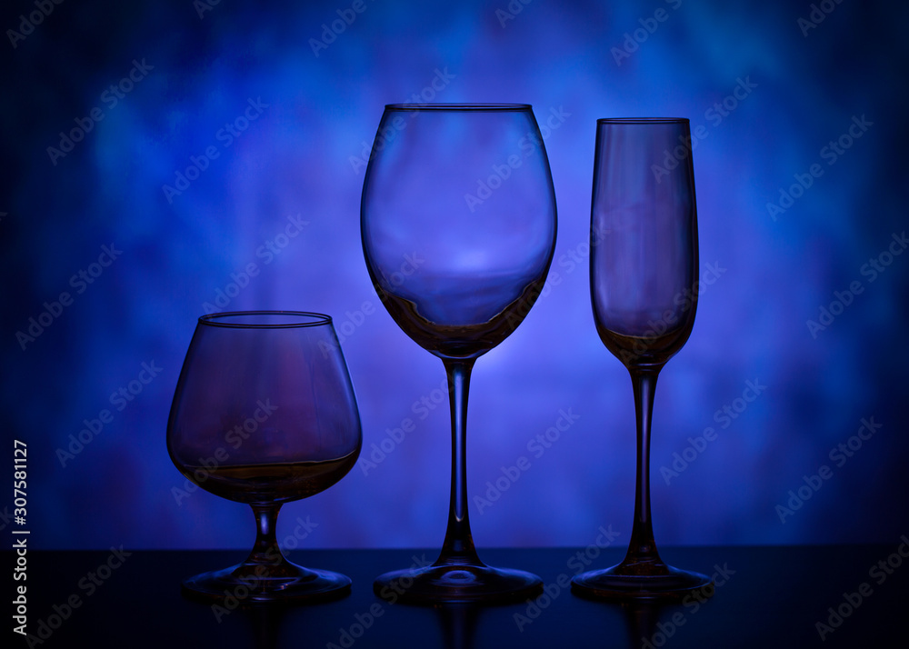 Silhouettes of wine glasses. Beautiful glass goblets. Collection of beautiful glasses on a blue background.